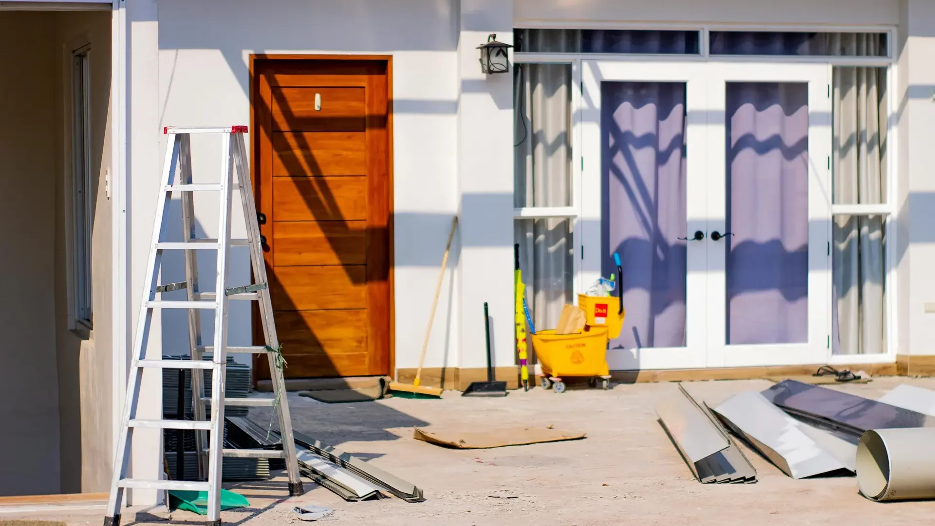 Front entrance of a house under renovation with tools and materials scattered around.